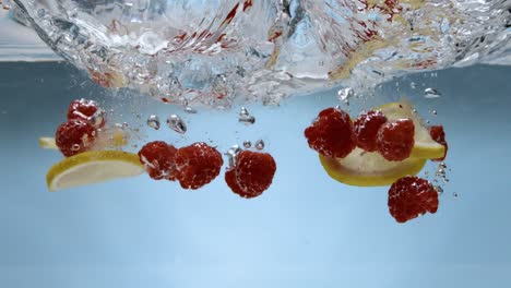 frambuesas y limones golpeando la superficie del agua