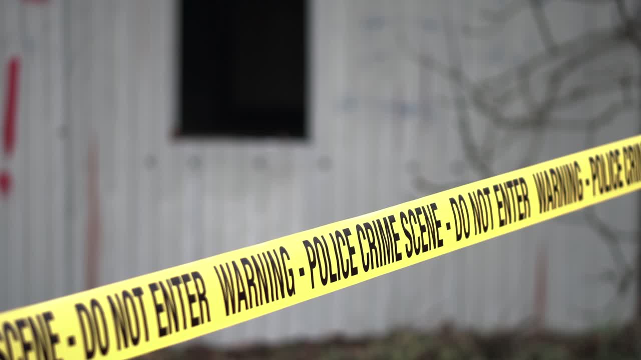 Police Crime Scene Tape Ribbon in Front of Rustic Building in Autumn