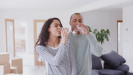 loving couple surrounded by boxes celebrating moving into new home with champagne