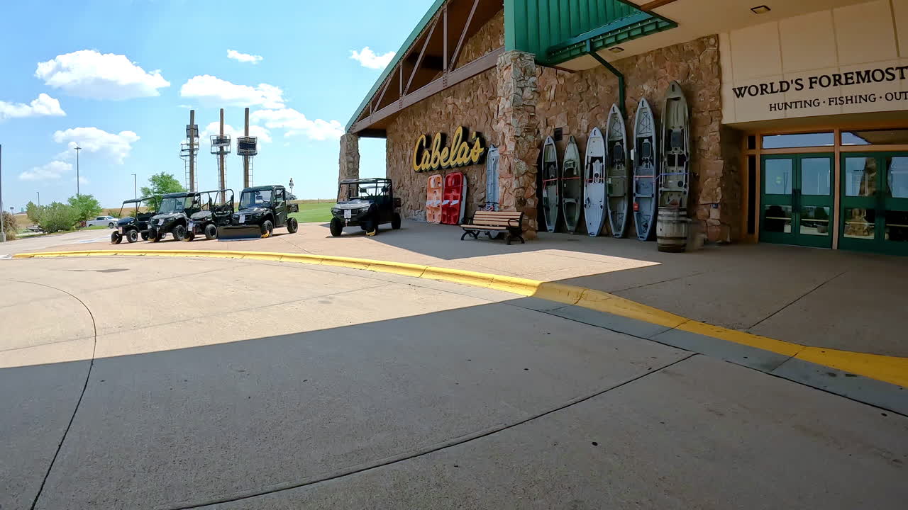 POV - Driving past the front entrance of Cabela's Outdoor Outfitters; fishing boats, kayaks, hunting blinds and ATVs on display; concepts of outdoor life and adventure