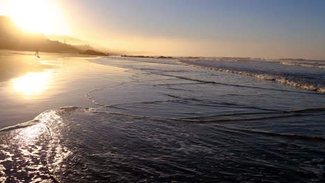 early morning sun rays reflecting off of wet sand on beach during sunrise, wilderness beach, south africa