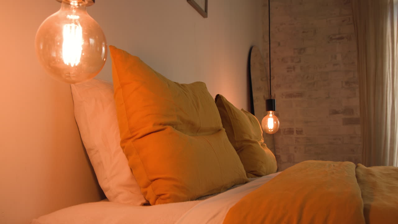 Cozy bedroom with warm lighting and soft orange pillows on bed, at home