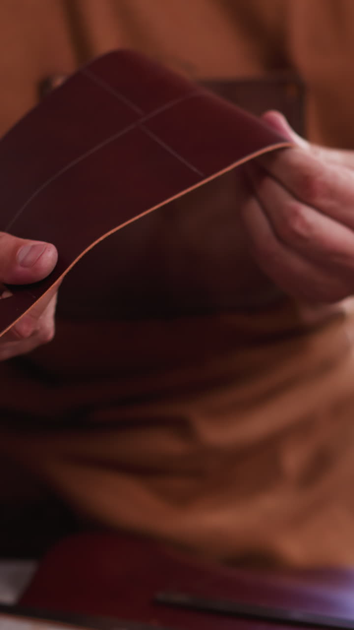 Master bends and turns leather detail of craft accessory in workshop close view. Leather goods manufacturer makes original item in studio. Manual work industry