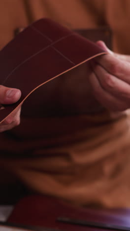 master bends and turns leather detail of craft accessory in workshop close view. leather goods manufacturer makes original item in studio. manual work industry
