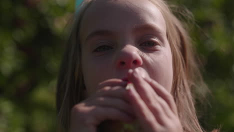 little girl eating a fresh apple outside in the sun