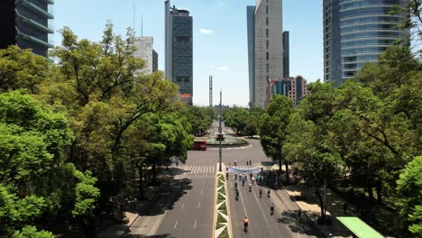 backwards-drone-shot-of-cyclists-exercising-on-reforma-avenue-in-mexico-city-during-Sunday