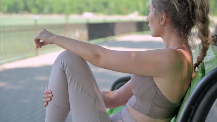 Woman in beige sportswear resting on a bench in the park