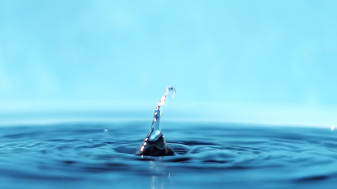 파란색 배경에 떨어지는 물방울과 함께 물 표면의 느린 모션 4k 비디오.