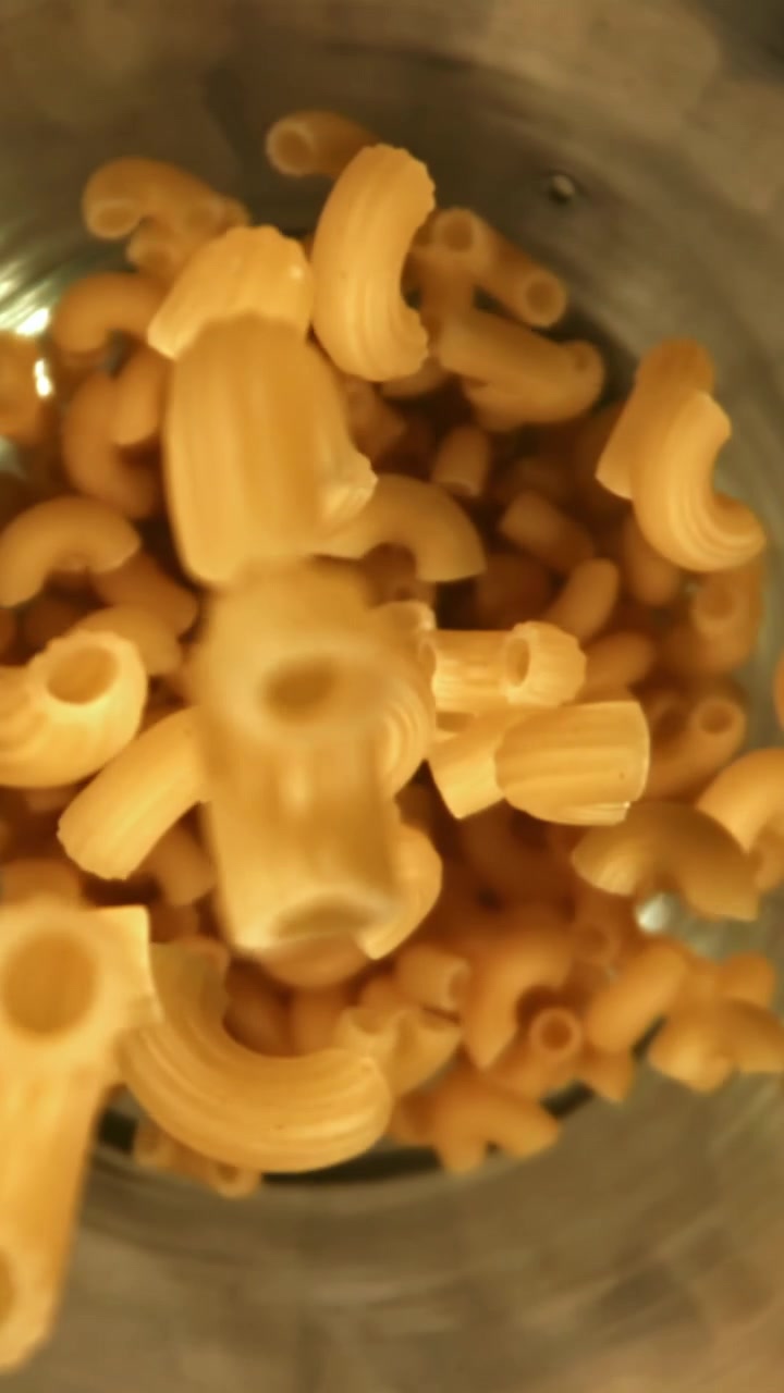 Maccheroni secchi che cadono in un contenitore al rallentatore