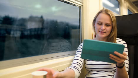 woman with touchpad and tea in train