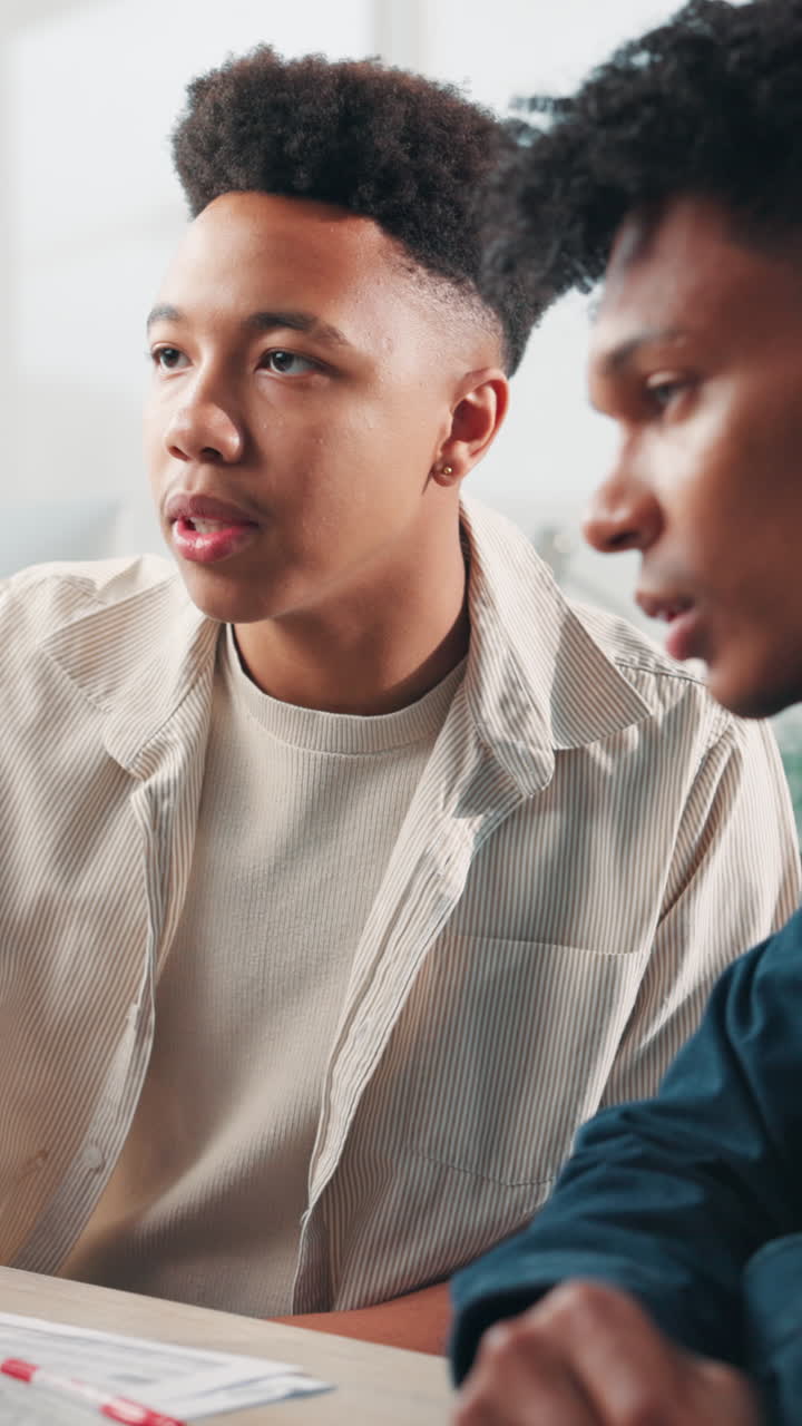 Two Young Men Discussing Ideas and Collaborating at a Desk