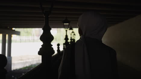 black arabic woman walks looking at river along riverside