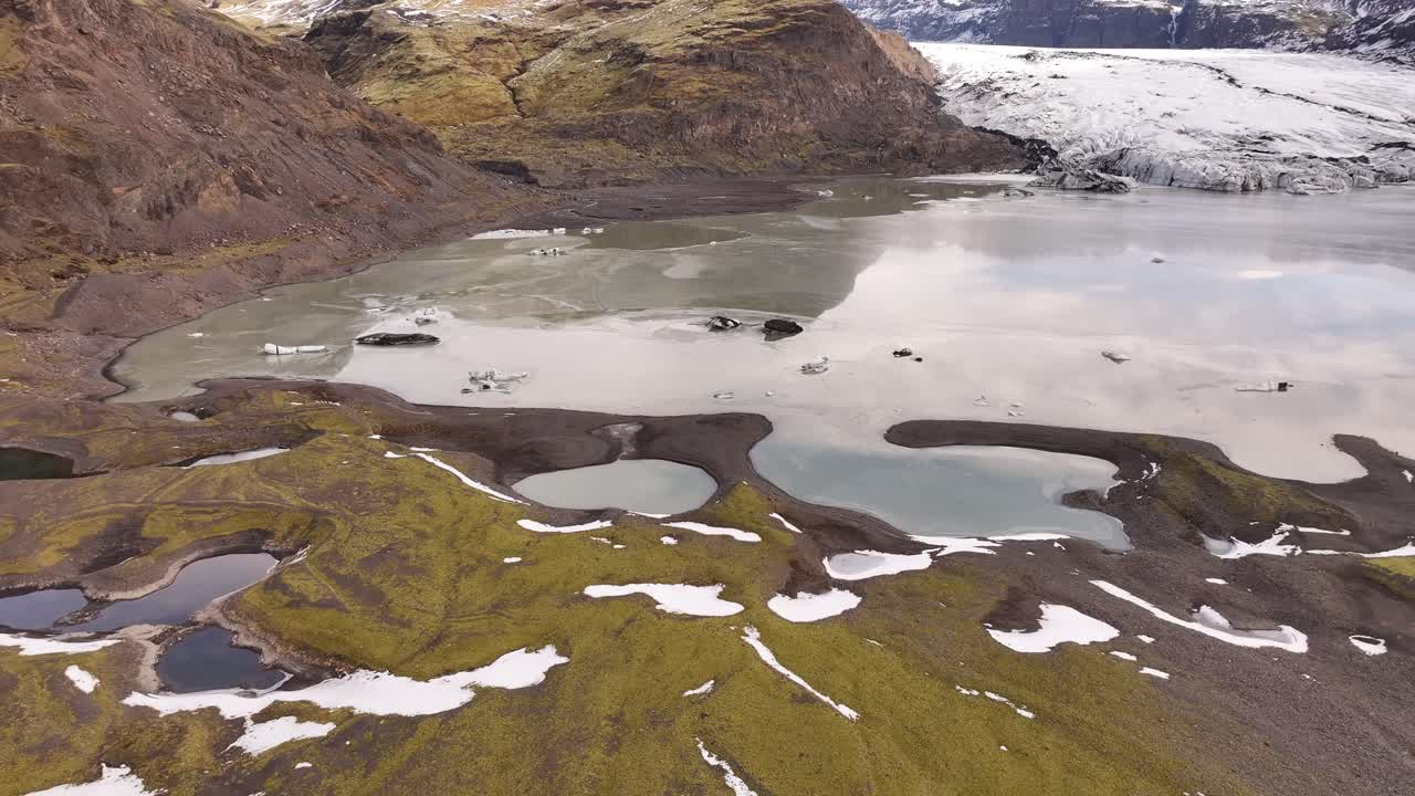 Aerial view of the Sólheimajökull glacier and surrounding frozen lagoon in Iceland.