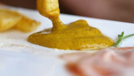 close-up of a french fry dipping in mustard