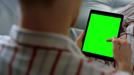 desplazamiento del dedo pantalla de la tableta verde de cerca. gerente uso de computadora digital en el hogar