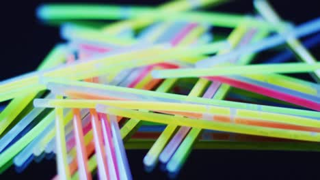 animation of multiple colorful neon glow sticks over black background