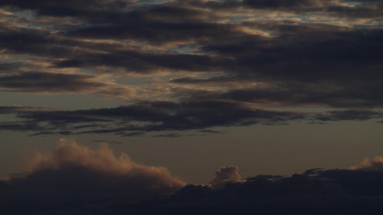 Céu crepuscular tênue com nuvens em camadas flutuando lentamente enquanto a última luz quente se desvanece perto do horizonte