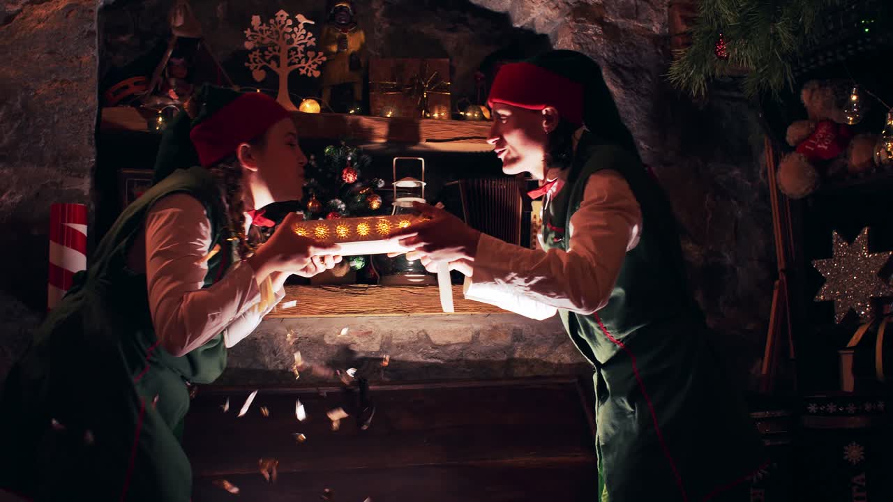 Christmas Elves in a dark room take an old book from a luminous chest
