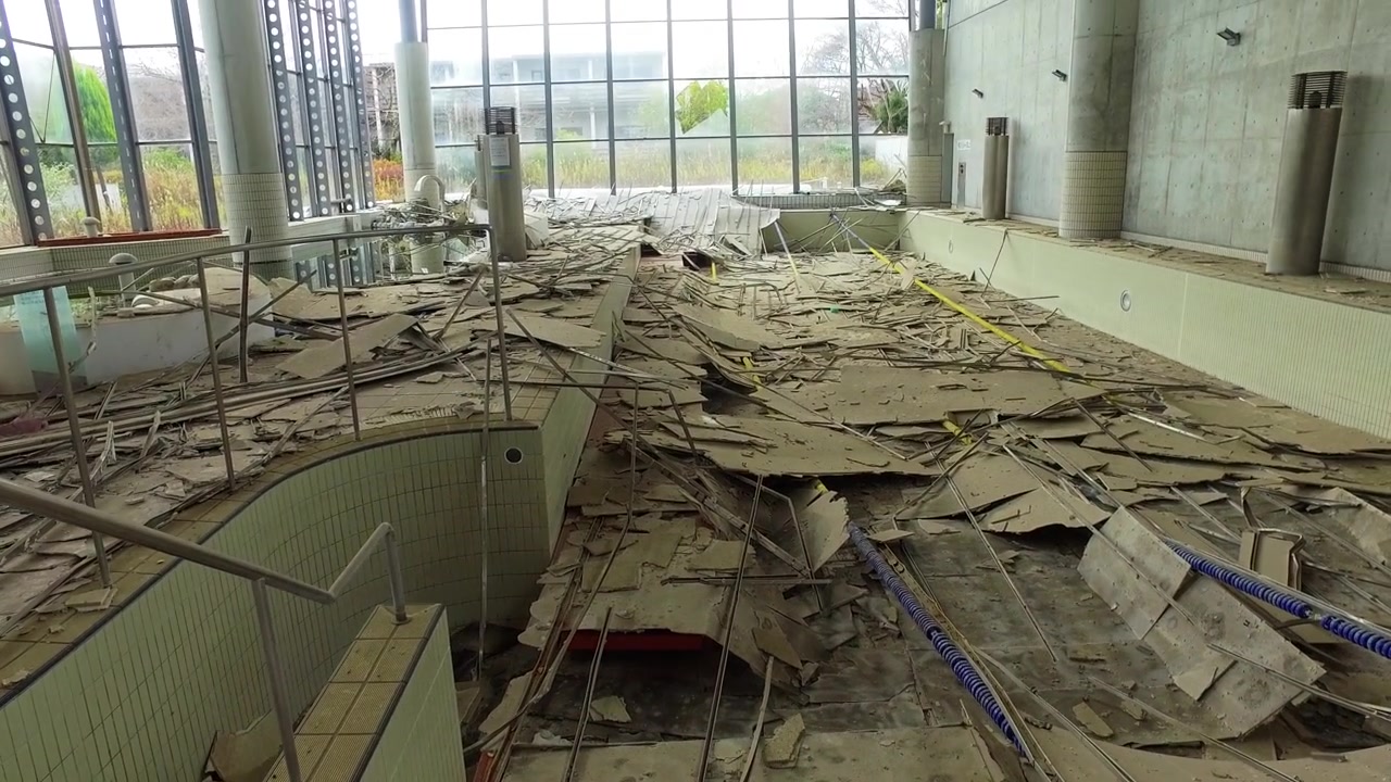 Somber handheld exploration of a derelict aquatic center filled with wreckage.