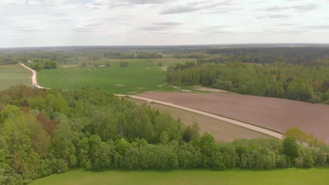 drone flying over countryside landscape in kurzeme, latvia, cloudy day
