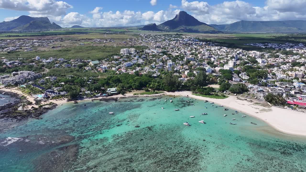 Aerial view of a coastal town with turquoise water and mountains
