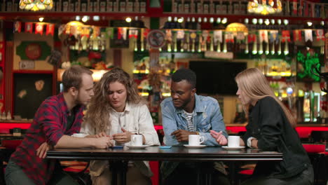 modern multiethnic couples show each other travel photos while sitting in a cafe