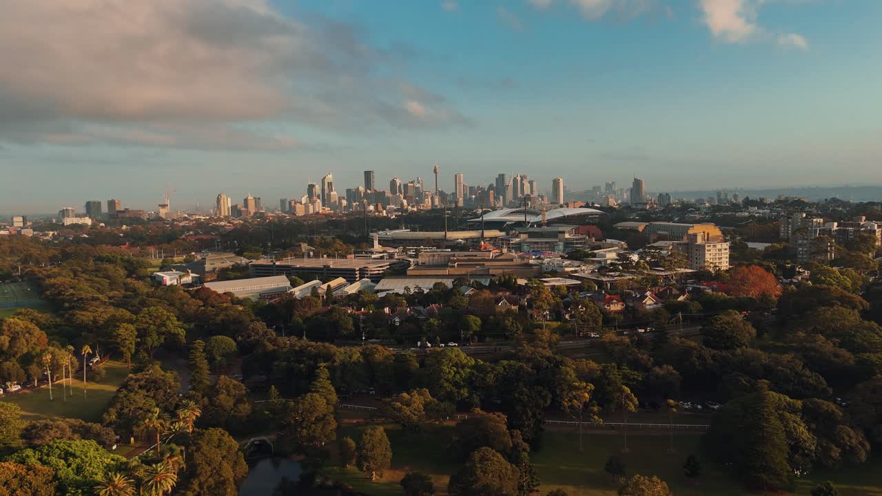 Wide aerial pullback of Centennial Park parklands and city skyline in distance with lakes and open lawns in Sydney NSW Australia
