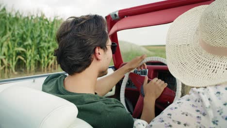 vista trasera de una pareja conduciendo un coche entre los campos