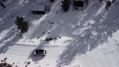 Familie-Verlässt-Tagsüber-Die-Berghütte-Auf-Einer-Schneebedeckten-Hinterlandstraße,-Luftaufnahme-Von-Oben-Nach-Unten