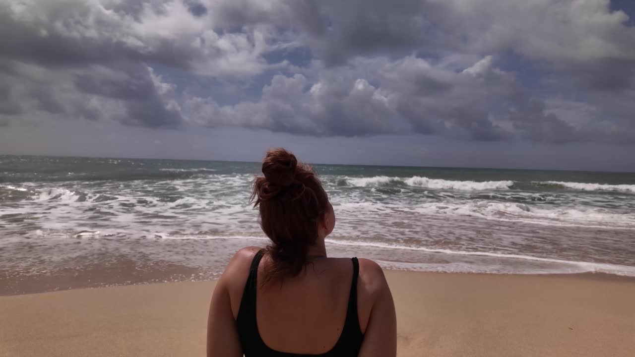 Woman on the beach looking at ocean waves, sun therapy outdoor relaxing holiday mind clearing