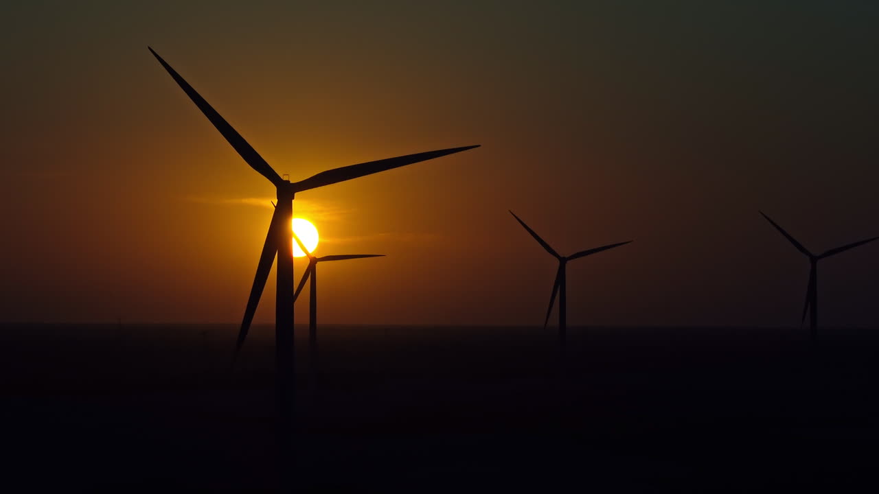 Long lens drone shot of silhouettes of windturbines during a sunset