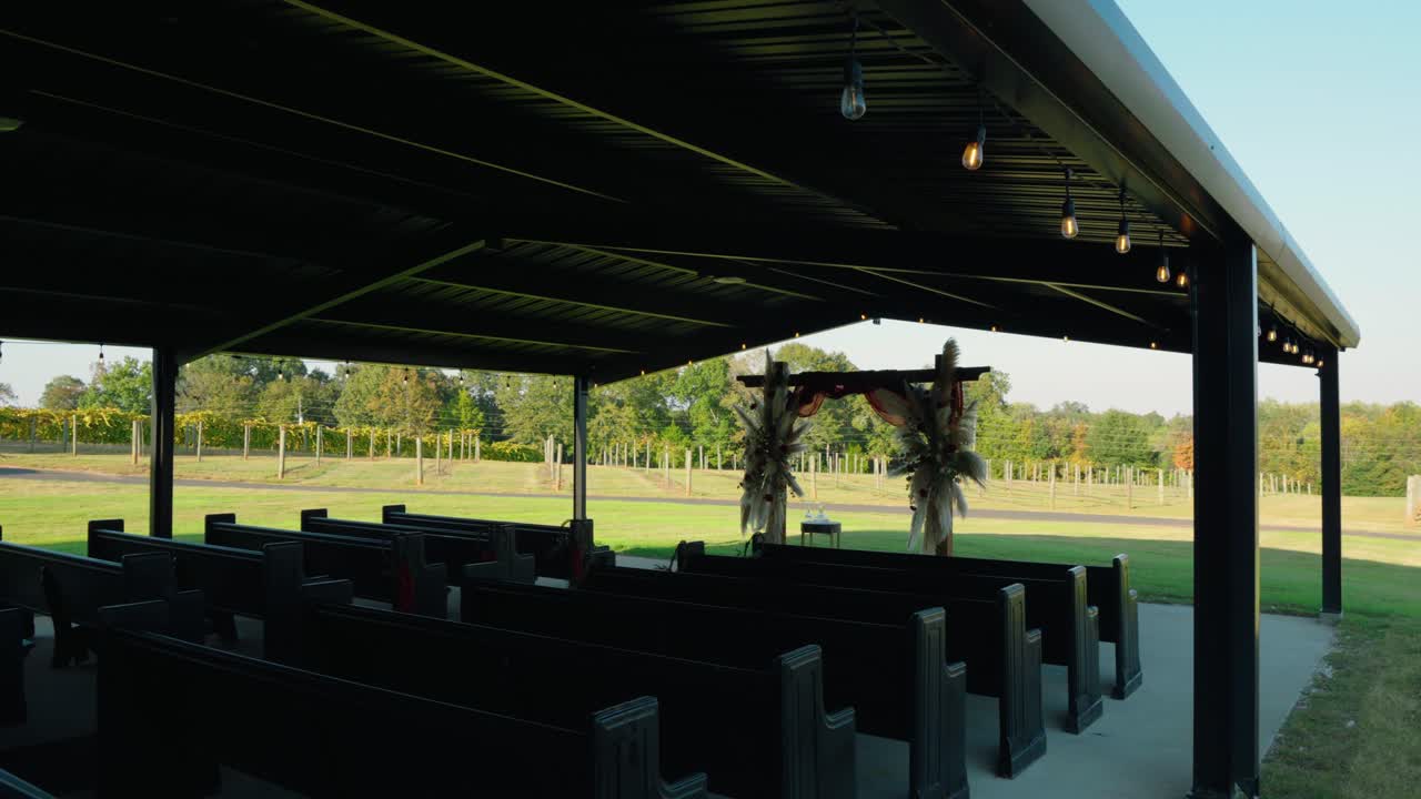 Side view of a wedding ceremony pavilion at a South Georgia winery. The open-air design offers views of the vineyard in the background. Captured with smooth gimbal movement.