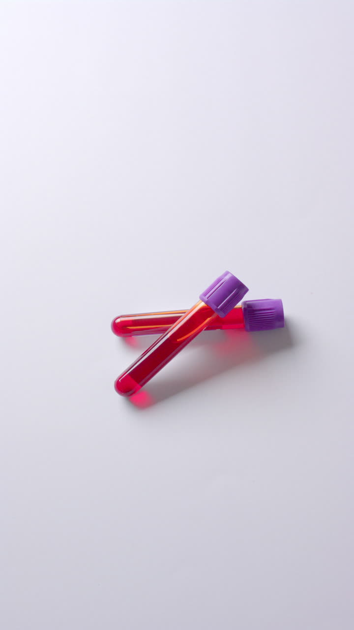 Vertical video of blood samples on white background with copy space, slow motion