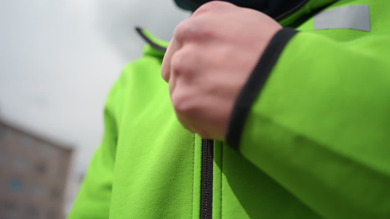 운동복 재킷 핏을 개선하는 데 집중하는 손, 경기 전에 스포츠웨어를 준비하는 손의 디테일 뷰, 활기 넘치는 경기 전 분위기에서 스포츠 재킷을 사용자 지정하는 손을 클로즈업해서 보여줍니다.