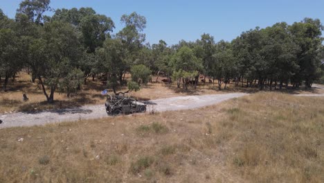 israel army infantry squad soldiers on humvee vehicle driving through training ground country road, aerial tracking shot