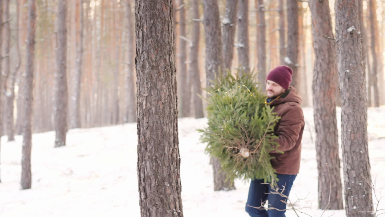 수염을 기른 세련된 아빠가 젊은 아내와 아이가 타고 있는 차체에 새해 나무를 싣고 있습니다.