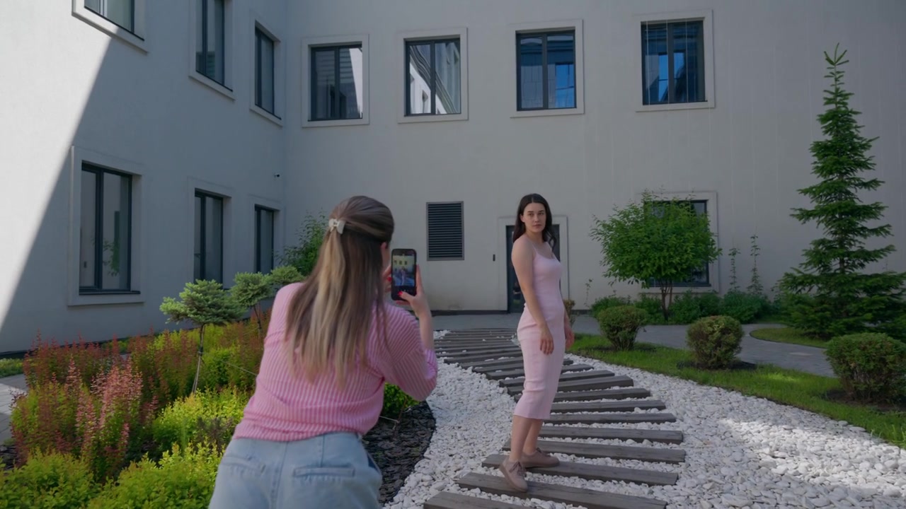 Ung kvinde tager billeder af sin veninde i en have
