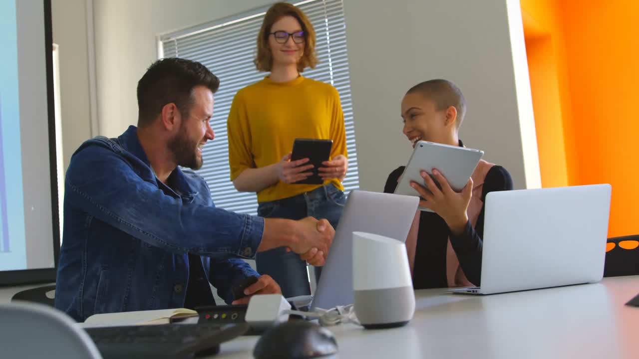 jóvenes colegas de negocios caucásicos estrechando la mano entre sí en la oficina 4k