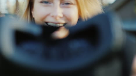 una hermosa mujer invita al mundo de la realidad virtual sonriendo poniéndose un casco 3d en la cámara 4