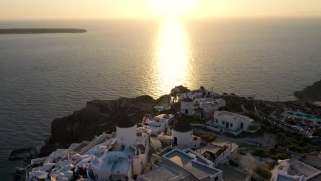 smooth panning shot over windmill in oia built on a cliff during sunset, santorini island, cyclades, greece