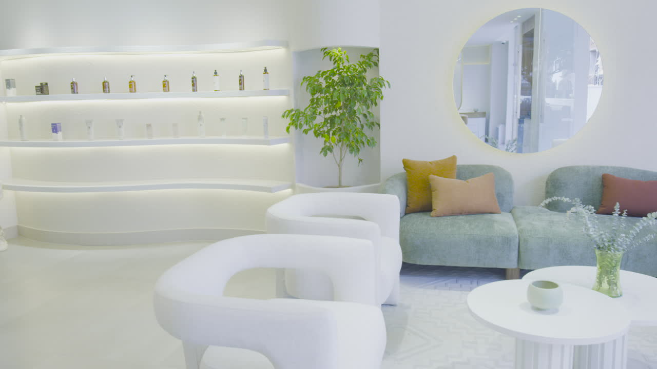 A soft panning shot reveals a modern reception room with a sleek bookshelf. The space is well-lit, with a clean design and decorative details.