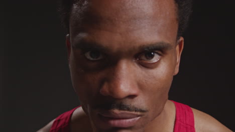 Close-Up-Portrait-Of-Serious-Male-Boxer-Wearing-Vest-Walking-Towards-Camera-And-Into-Focus-Training-For-Sports-Event-Against-Black-Studio-Background-1