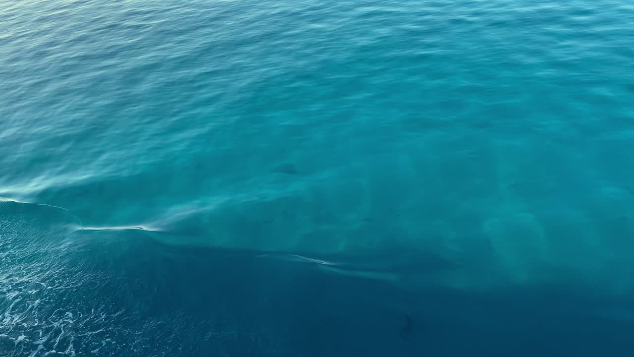 Superficie di onde d'acqua blu, bellissimo sfondo con spazio per il testo. Sfondo calmo e tranquillo di onde marine con vista aerea. Texture della superficie dell'acqua dell'oceano vicino alla nave, onde che scorrono e sfondo per vacanze estive.