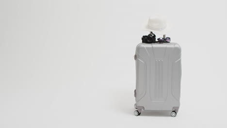 close up of suitcase, camera, sunglasses and sunhat with copy space on white background