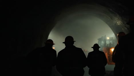 construction workers in a dark tunnel with machinery