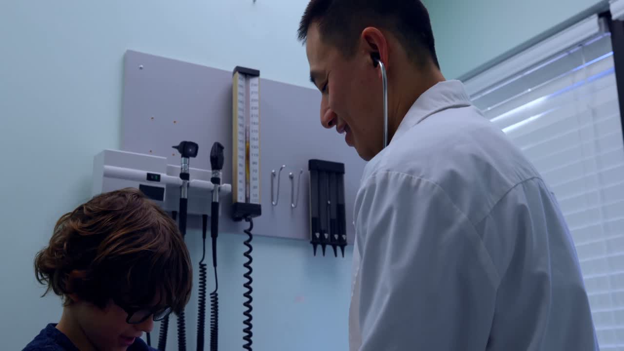 vista lateral de un joven médico asiático controlando la presión arterial de un paciente caucásico en la clínica 4k