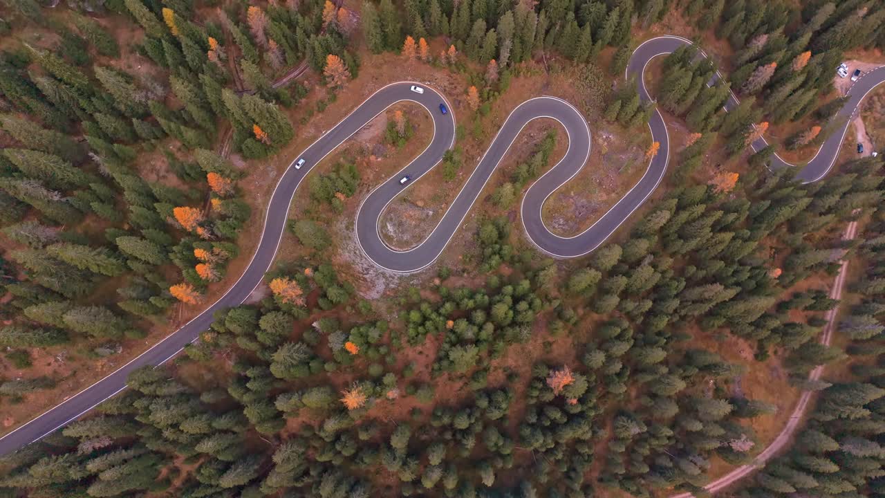 Dronekuva mutkikkaasta Snake Roadista syksyisen metsän halki, Dolomitit, Italia