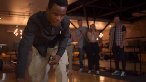 multi ethnic group of friends in a bowling club portrait of a black man throws a ball and knocks out a strike