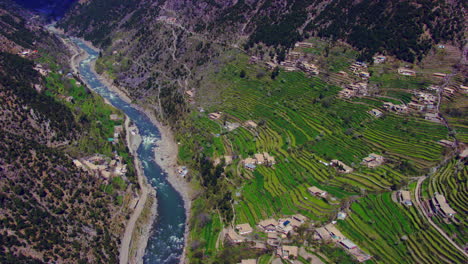 aerial flight over the village houses with beautiful scenes of mountains and blue fresh river, as well as charmingly crafted greenery with a roads