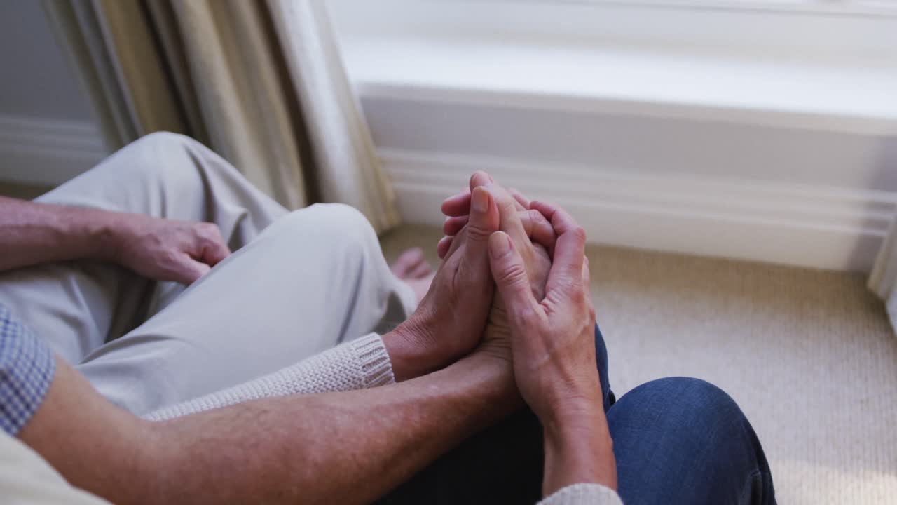 손을 잡고 거실에 앉아있는 행복한 고위 백인 부부의 중간 섹션